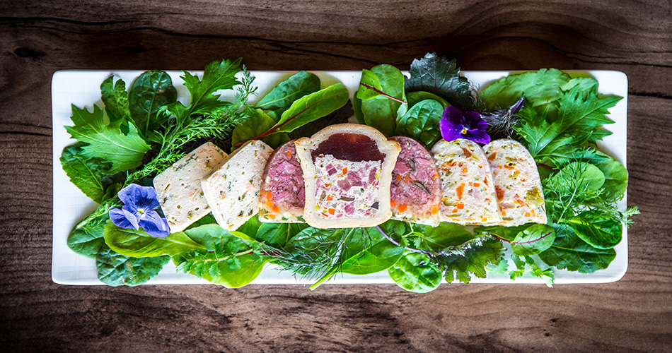 Fleischpasteten angerichtet auf Salatblättern auf einem weissen Teller