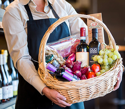 Mitarbeiterin in einem Frischeparadies hält einen Geschenkkorb hoch